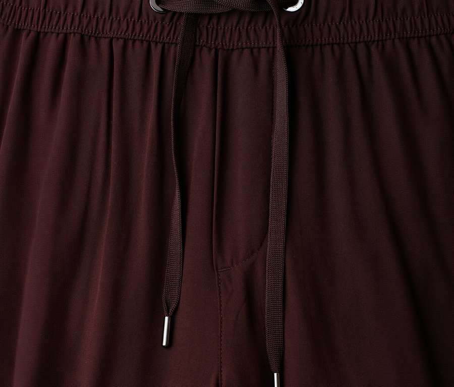 Gros plan sur la taille d'un pantalon culotte 7/8 Street One « EMMA » marron, avec une ceinture élastique et un cordon de serrage marron à embouts et œillets métalliques argentés.