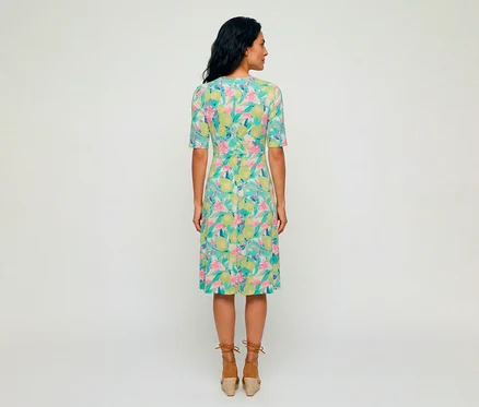 Femme vue de dos portant une robe en jersey Olsen avec un motif coloré de citrons verts et de fleurs roses, associée à des sandales compensées espadrilles marron.