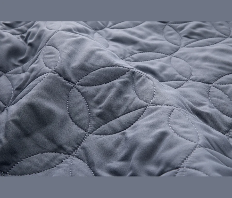 Tissu gris matelassé avec un motif de lignes courbes qui se croisent.