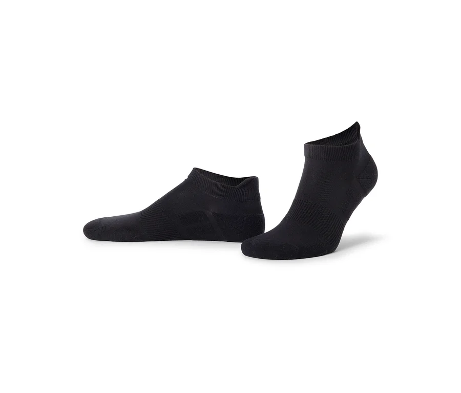 Deux chaussettes de cheville noires, l'une posée à plat et l'autre debout, sur un fond blanc.