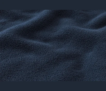 Tissu polaire bleu foncé à la surface douce et texturée, drapé en plis délicats.