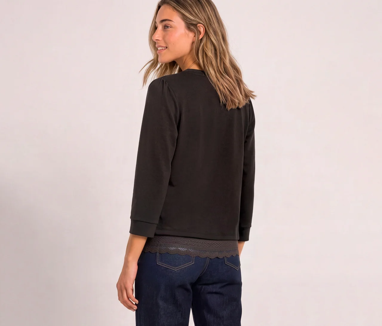 Une femme de dos, regardant par-dessus son épaule droite, porte un T-shirt en jersey 3/4 Street One marron avec des manches bouffantes et un jean foncé.