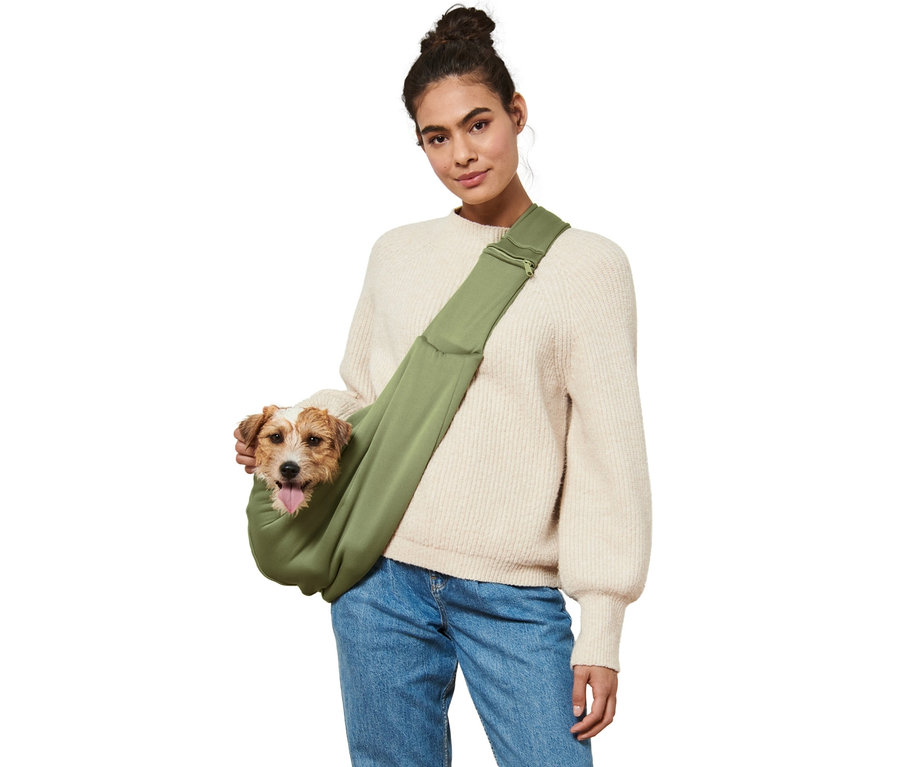 Femme avec chien marron dans un sac de transport pour animaux vert.