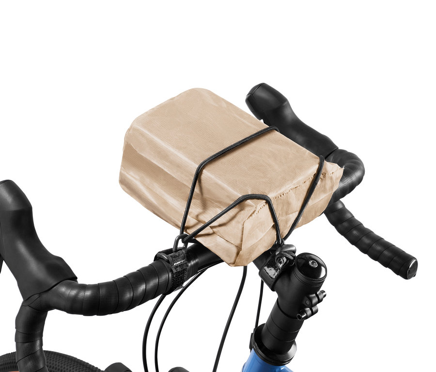 Sac en papier marron fixé sur le guidon du vélo avec une sangle de fixation.