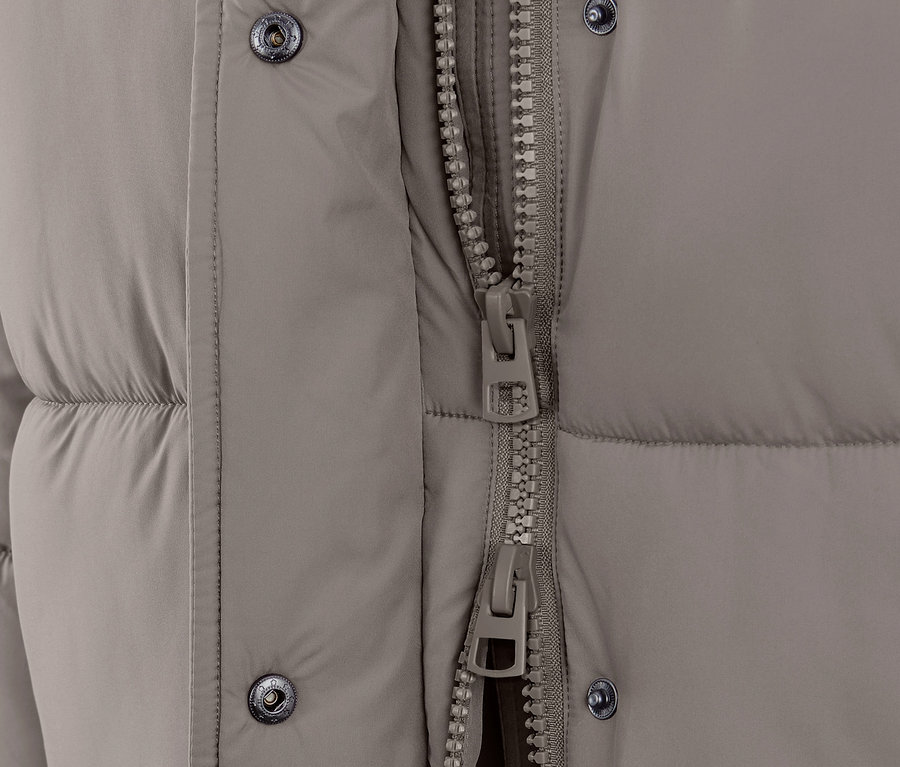 Gros plan sur un manteau matelassé à capuche taupe avec une fermeture éclair.