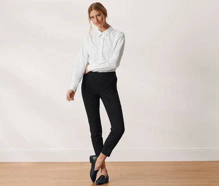 Femme posant en chemise blanche et pantalon stretch à pois noir.