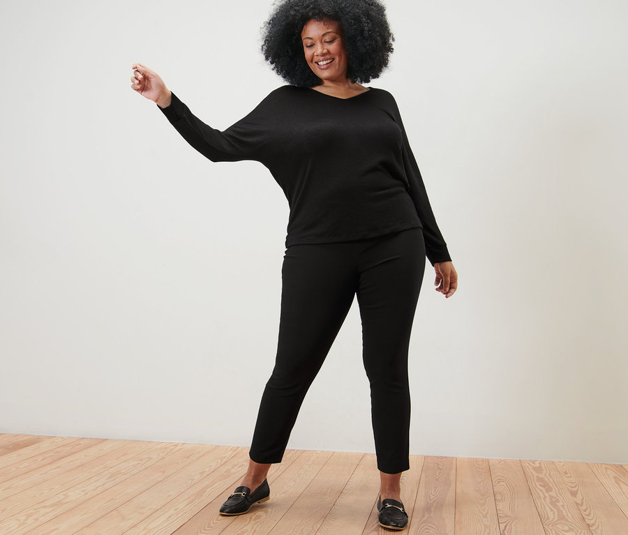 Femme posant en t-shirt manches chauve-souris noir et pantalon stretch noir.