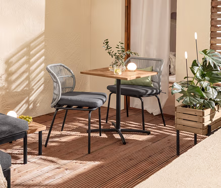 Balcon aménagé avec un ensemble lounge flexible « Elin », une table de balcon, des chaises avec tressage textile, 2 coussins d'extérieur, une caisse à plantes et 2 piquets lumineux solaires.