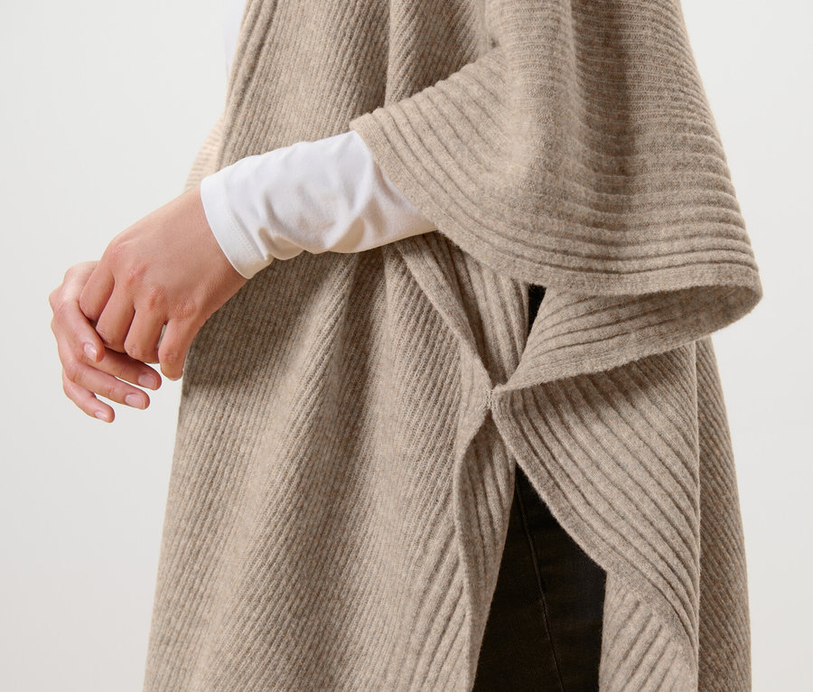 Détail d'une cape en tricot beige.
