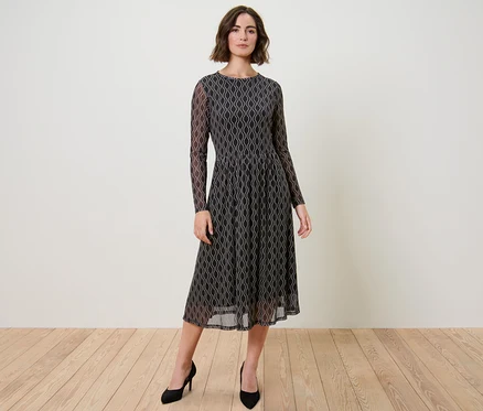 Femme posant en robe en mesh imprimée et escarpins noirs.