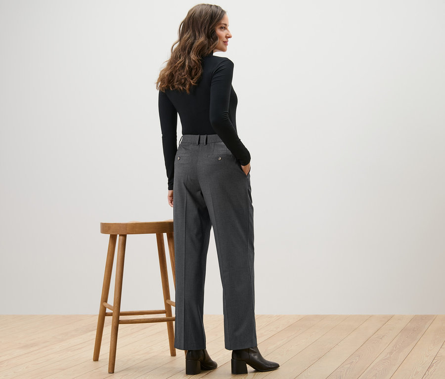 Une femme, vue de dos, porte un haut noir et un pantalon tissé confortable.