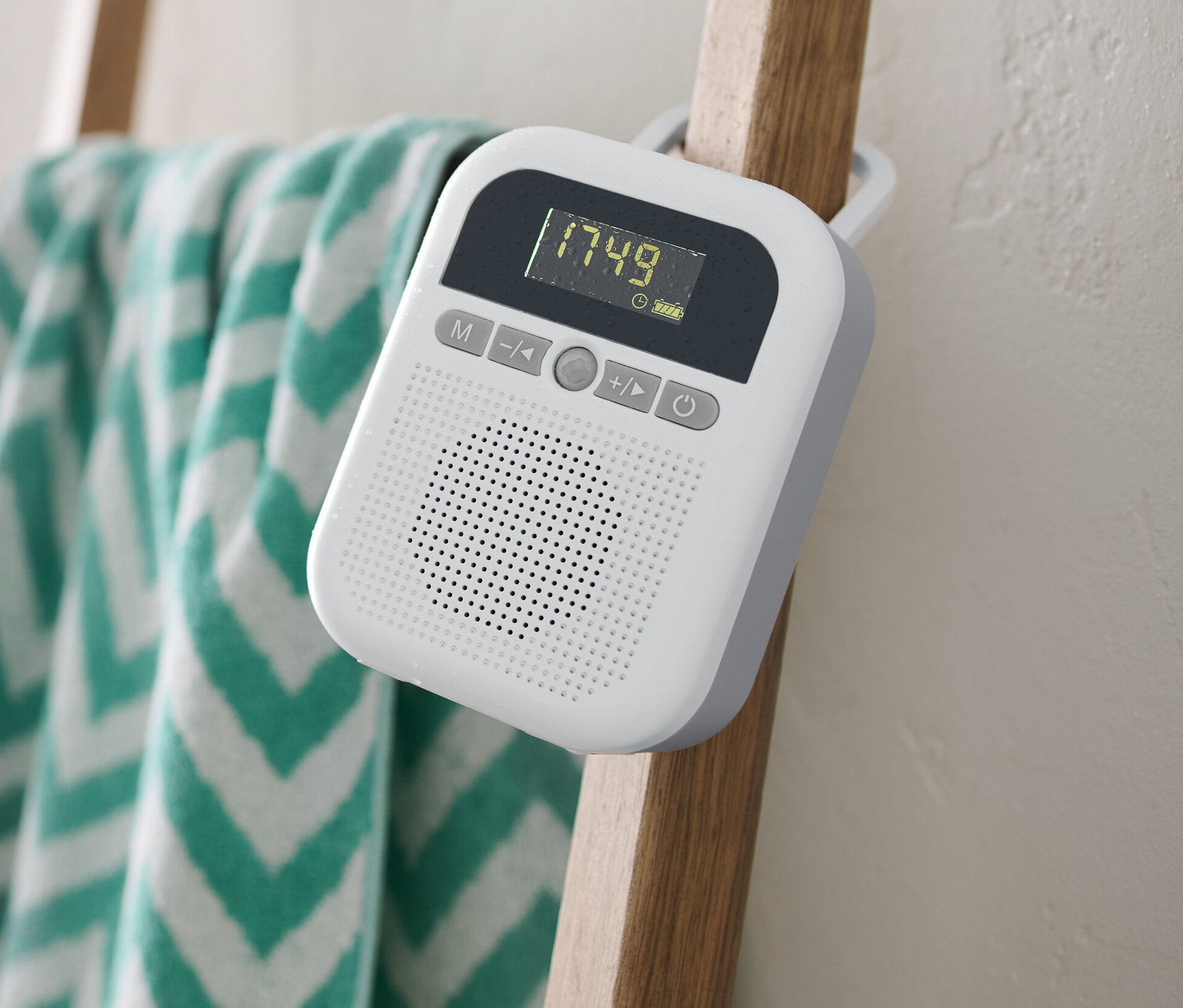 Un radio de salle de bains blanc est suspendu à une échelle en bois sur laquelle est accrochée une serviette.