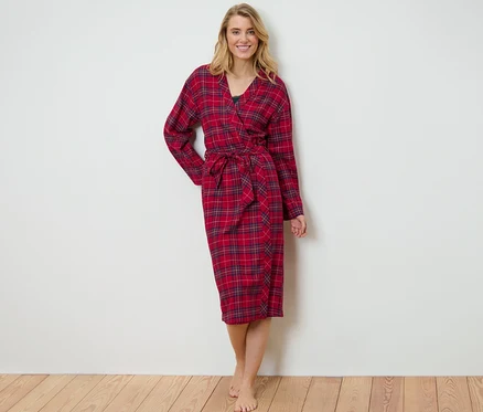 Une femme blonde portant une robe de chambre en flanelle à carreaux rouge.