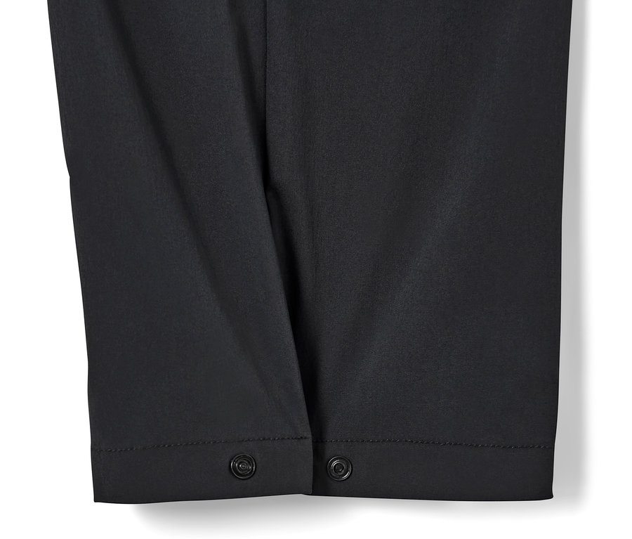 Gros plan sur un pantalon technique noir avec fermeture à bouton-pression.