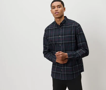Un homme pose en chemise de flanelle bleu marine.