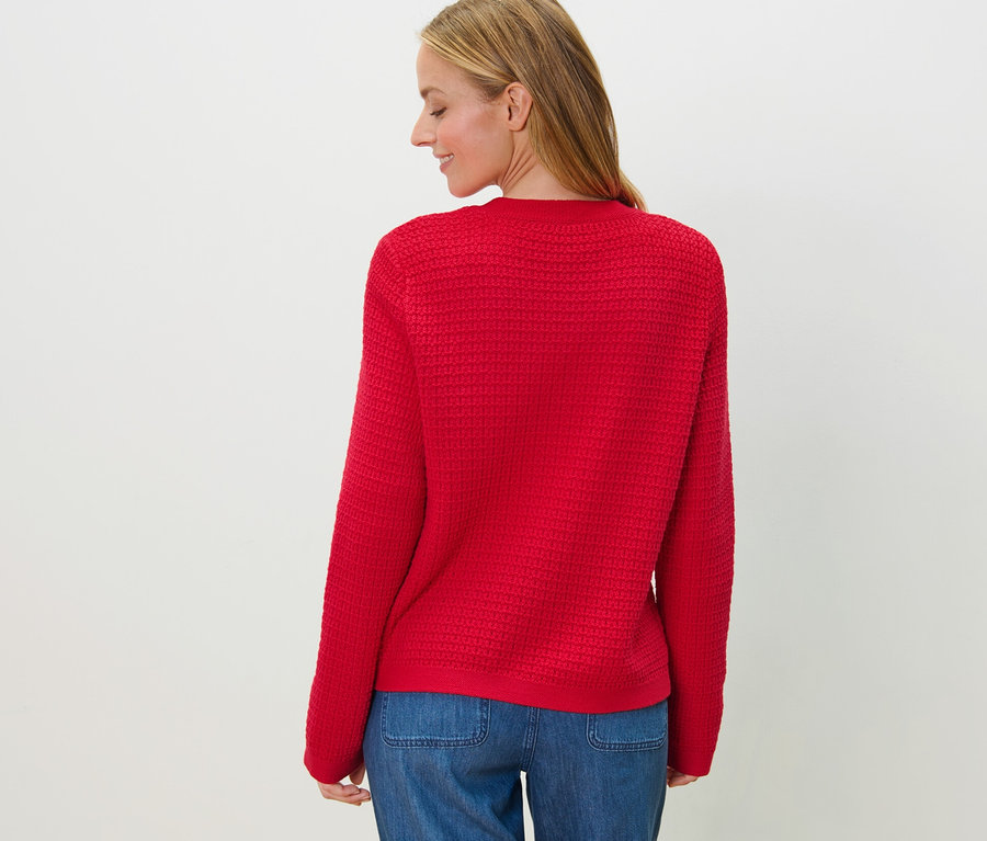 Vue arrière d'une femme blonde portant un cardigan en maille structurée rouge et un jean.