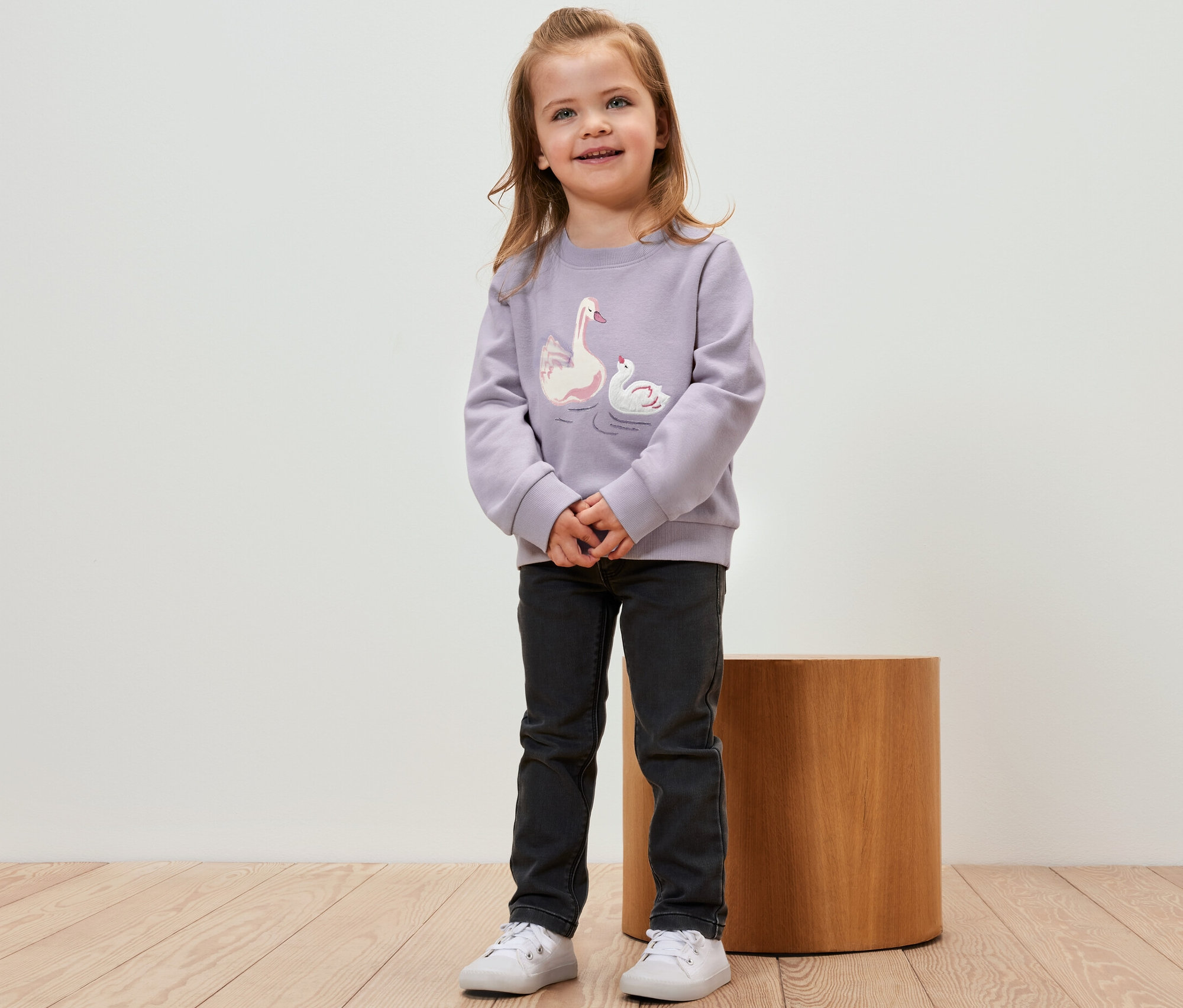 Une fille porte un sweat-shirt pour enfant avec intérieur gratté et motif cygne.