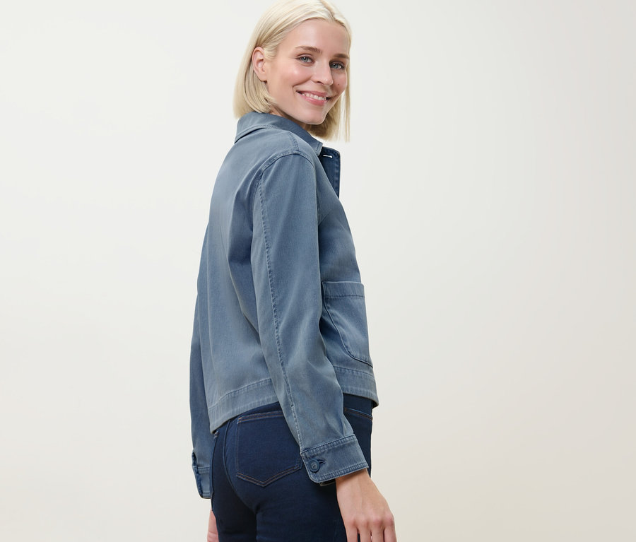 Une femme regardant par-dessus son épaule porte une veste en jersey aspect jean.