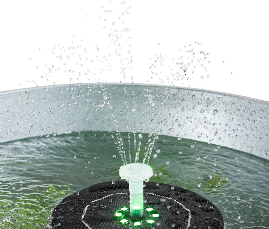 Une fontaine solaire flottante avec éclairage pulvérise de l'eau dans un seau en métal.