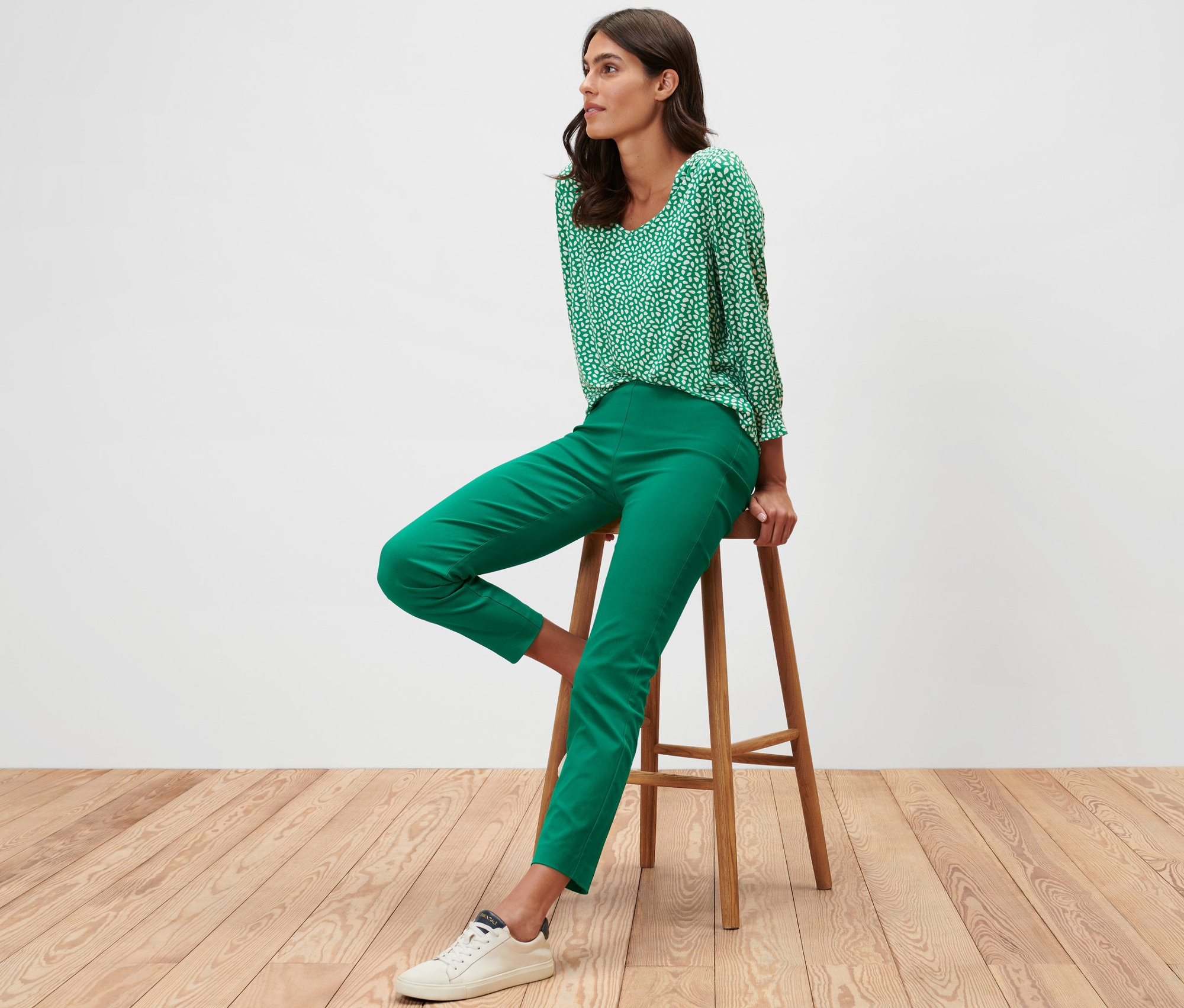 Femme assise sur un tabouret portant un pantalon stretch vert.