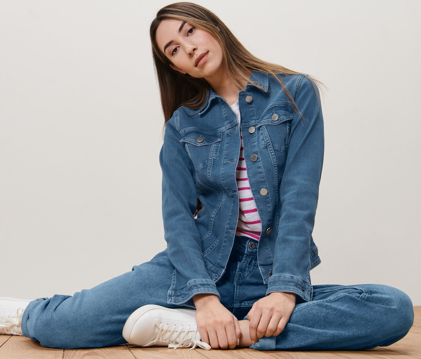 Femme assise par terre portant une veste en jean.