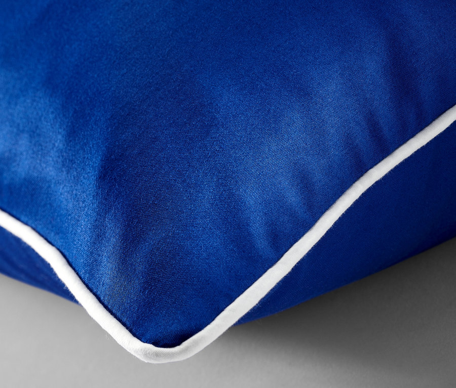 Gros plan d'une parure de lit en satin bleu de taille standard avec une bordure blanche.