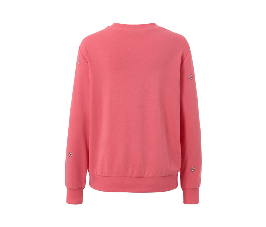 Vue détaillée d'un sweatshirt brodé rose avec des broderies florales sur les manches.