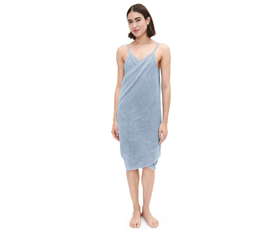 Une femme debout porte une robe de chambre bleu clair.