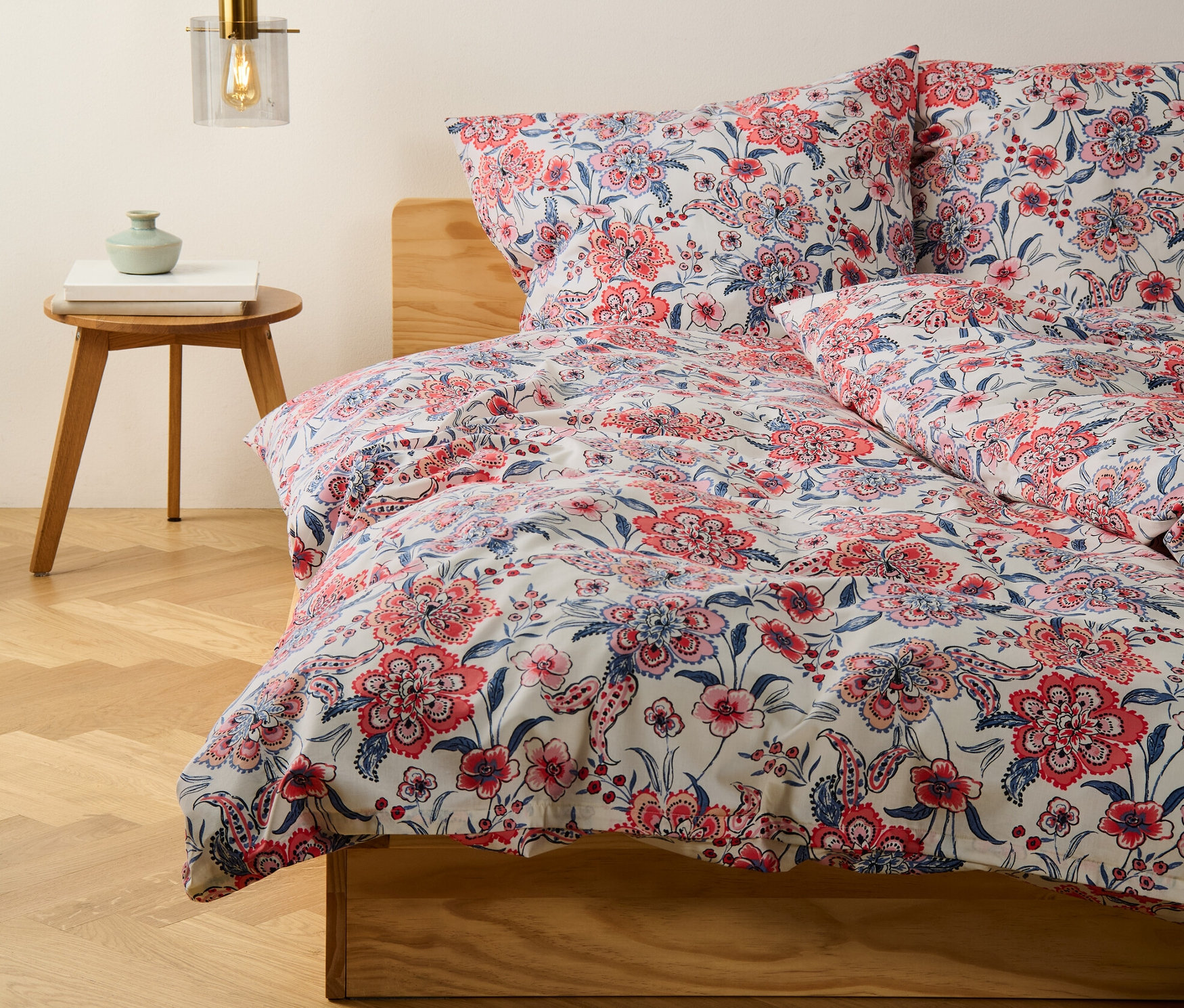 Gros plan sur une parure de lit en renforcé crème, grande taille et taille normale, avec un motif floral sur un lit.