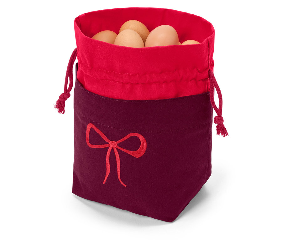 Sac en tissu avec bordure rouge et fond bordeaux, orné d'une broderie de nœud rouge, rempli d'œufs bruns.