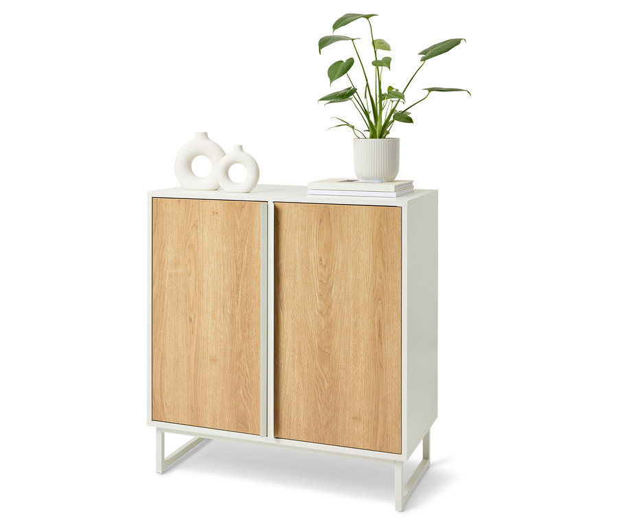 Armoire blanche avec portes en bois. Sur le dessus de l'armoire, il y a deux vases blancs, un livre et une plante dans un pot blanc.