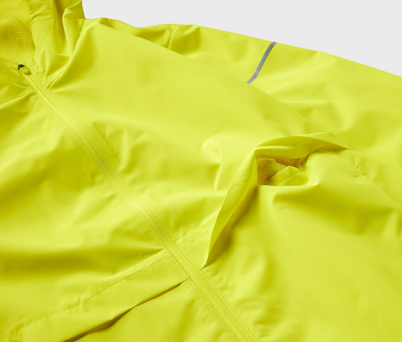 Détail d'une veste jaune texturée avec une fermeture éclair.