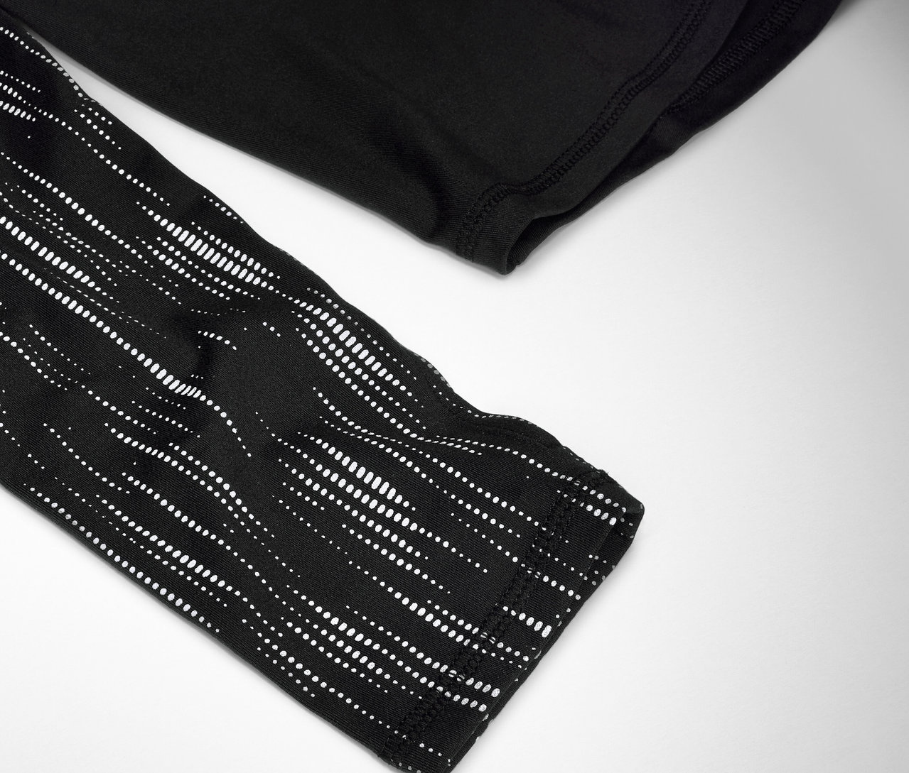 Gros plan sur un t-shirt noir à manches longues avec un motif à pois blancs sur la manche.