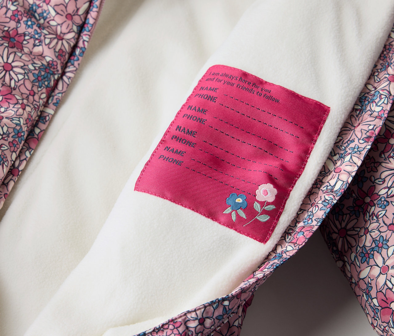 Détail d'une combinaison d’hiver pour bébé avec un motif floral et une étiquette pour le nom.