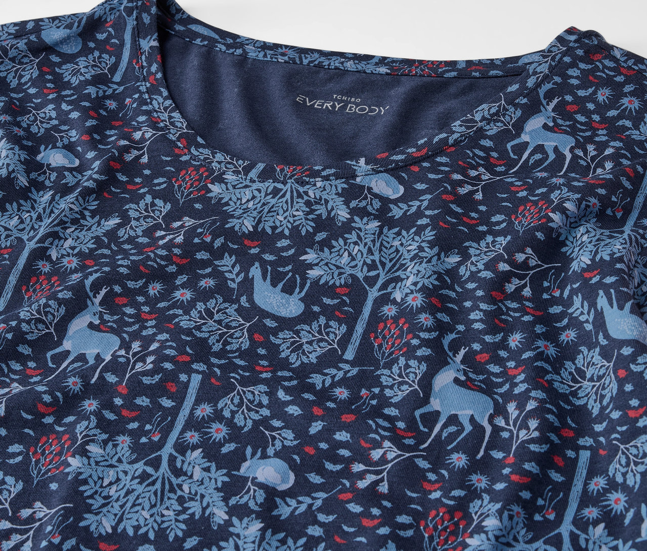 Détail d'un t-shirt bleu marine avec un motif d'arbres et d'animaux.
