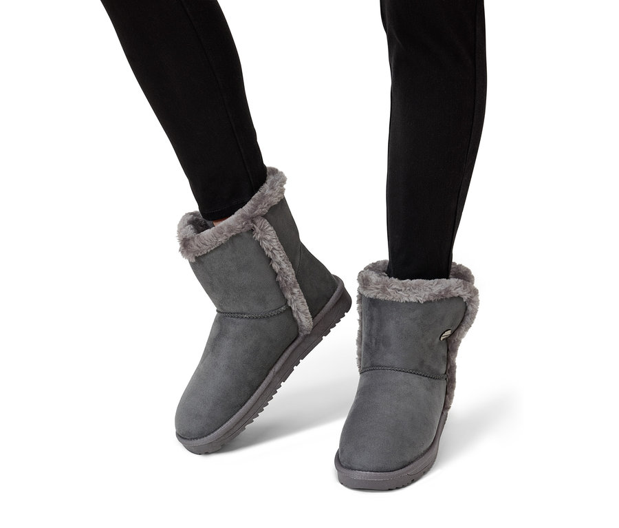 Jambes en jean noir portant des bottines grises avec une doublure en fourrure.