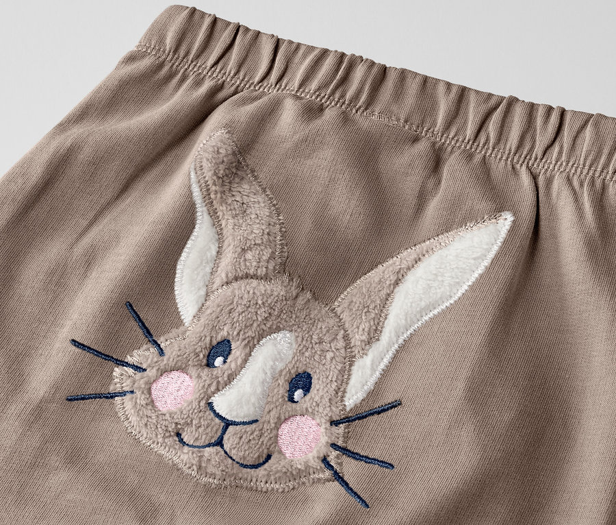 Gros plan d'un pantalon pour bébé avec un appliqué de lapin.