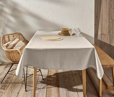 Une nappe lavable est posée sur la table. Des assiettes et des verres sont posés sur la table. Une chaise et un banc sont placés à la table.