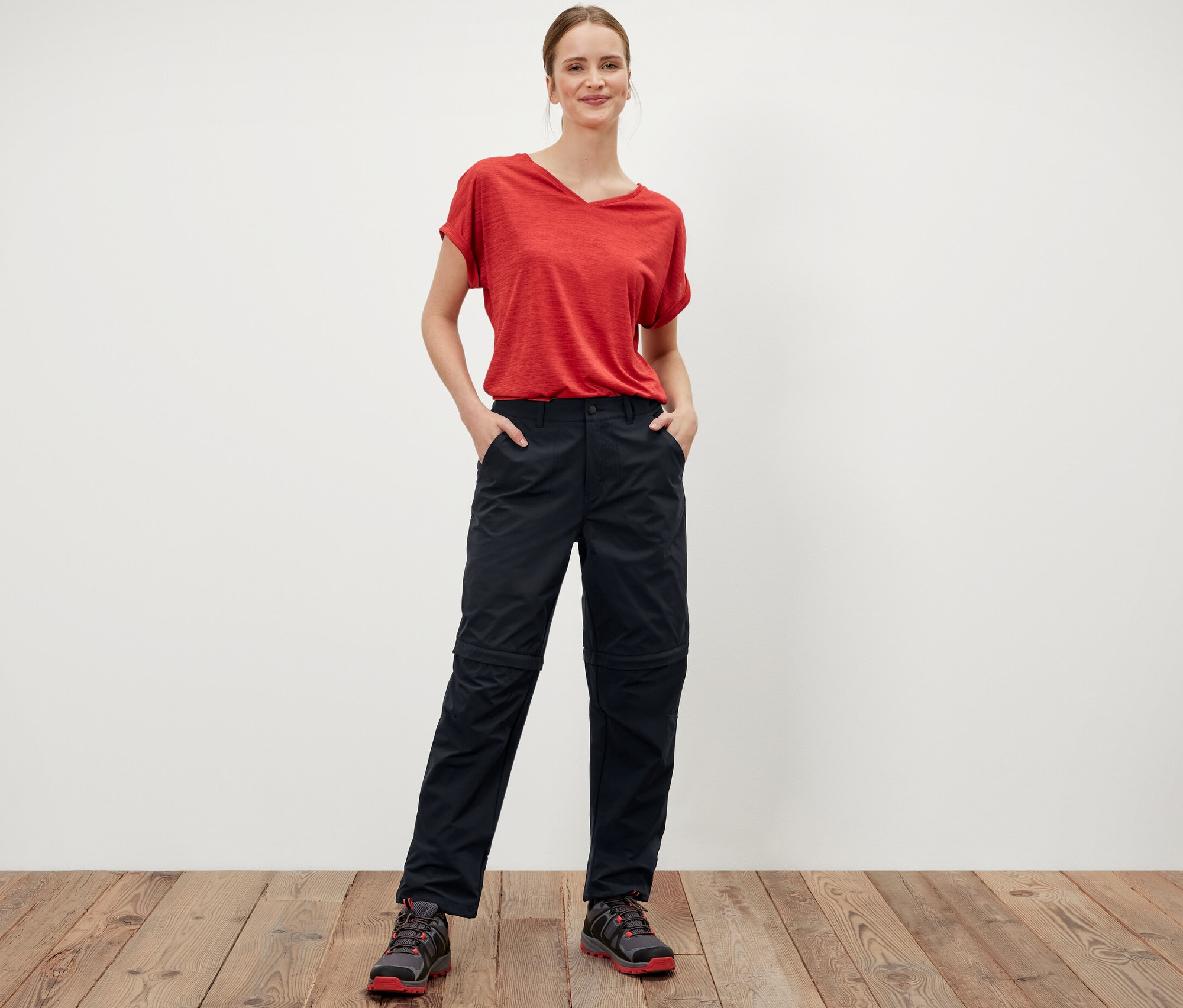 Femme debout, les mains dans les poches du pantalon fonctionnel 2 en 1 noir.