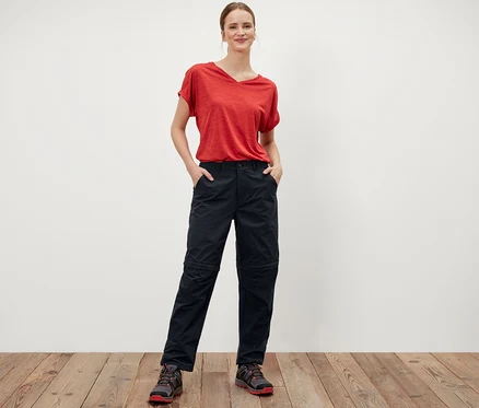 Femme debout, les mains dans les poches du pantalon fonctionnel 2 en 1 noir.