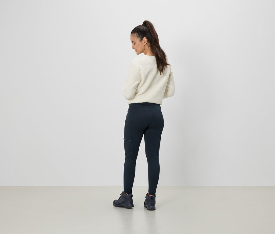 Femme portant un pull crème et un legging bleu marine avec une poche, vue de dos.