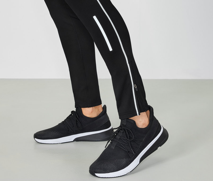 Chaussures de sport noir et blanc et pantalon noir avec détails réfléchissants.
