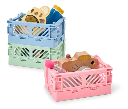 Pile de trois caisses de rangement en plastique de différentes couleurs contenant des jouets.