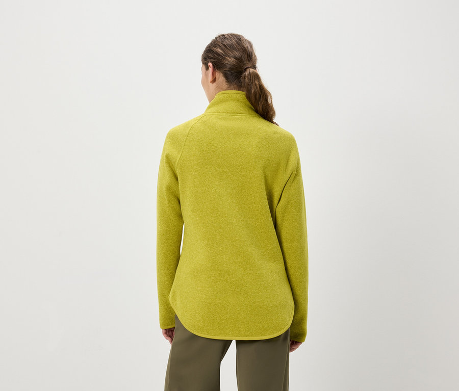 Vue arrière d'une femme avec une queue de cheval portant un pull en polaire jaune-vert et un pantalon vert olive.