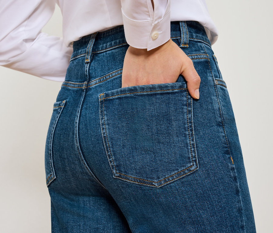 Vue arrière d'une femme avec une main dans la poche d'un Mom Jeans – Coupe »Nyla« bleu.