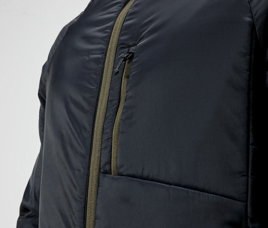 Détail d'une veste matelassée noire avec fermeture éclair verte.