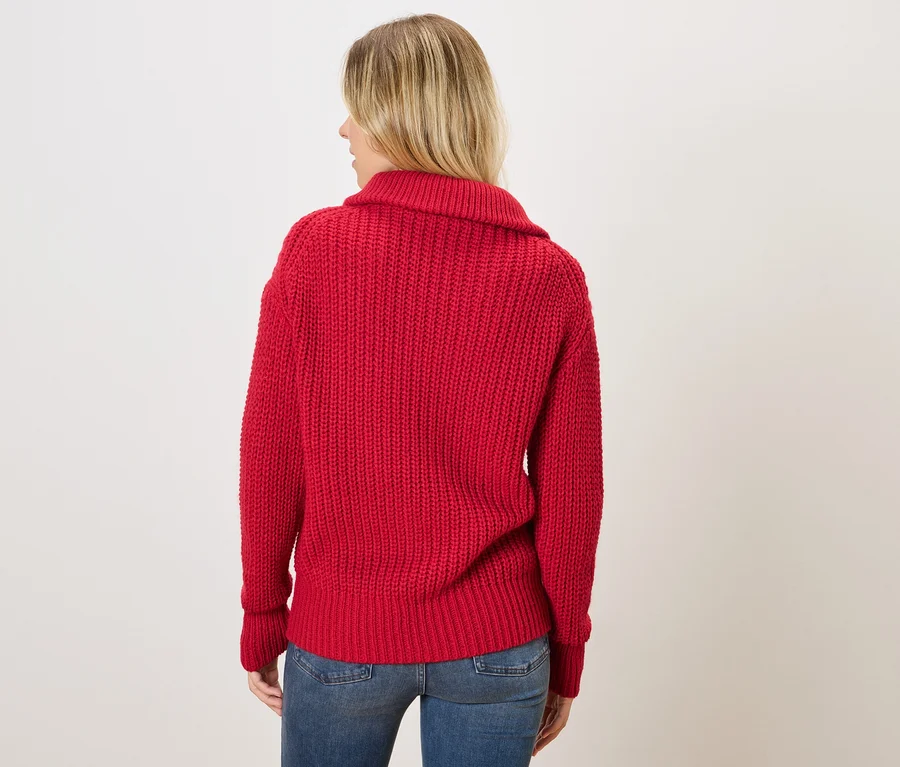 Femme de dos portant un pull en tricot rouge et un jean bleu.