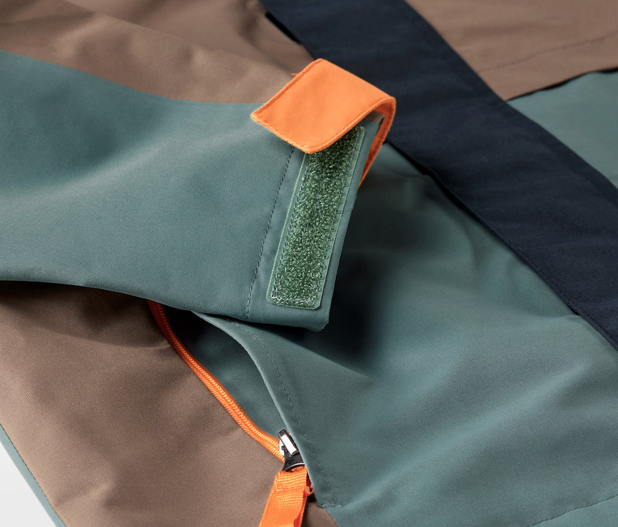 Gros plan sur une veste polyvalente pour enfant avec une poche zippée et une manchette à scratch.