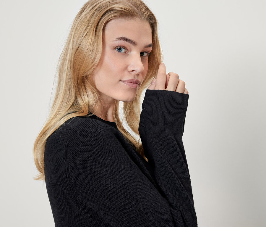Portrait d'une femme blonde portant un pull noir.