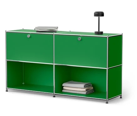 Meuble vert avec cadre argenté, livres et lampe.